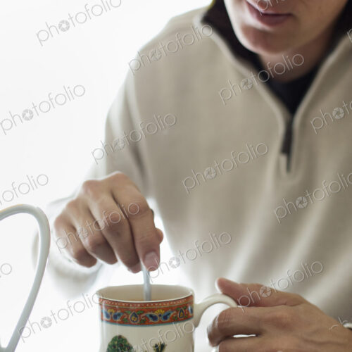 Man sitting at a table, stirring a cup of coffee. Man sitting at a table, stirring a cup of coffee.