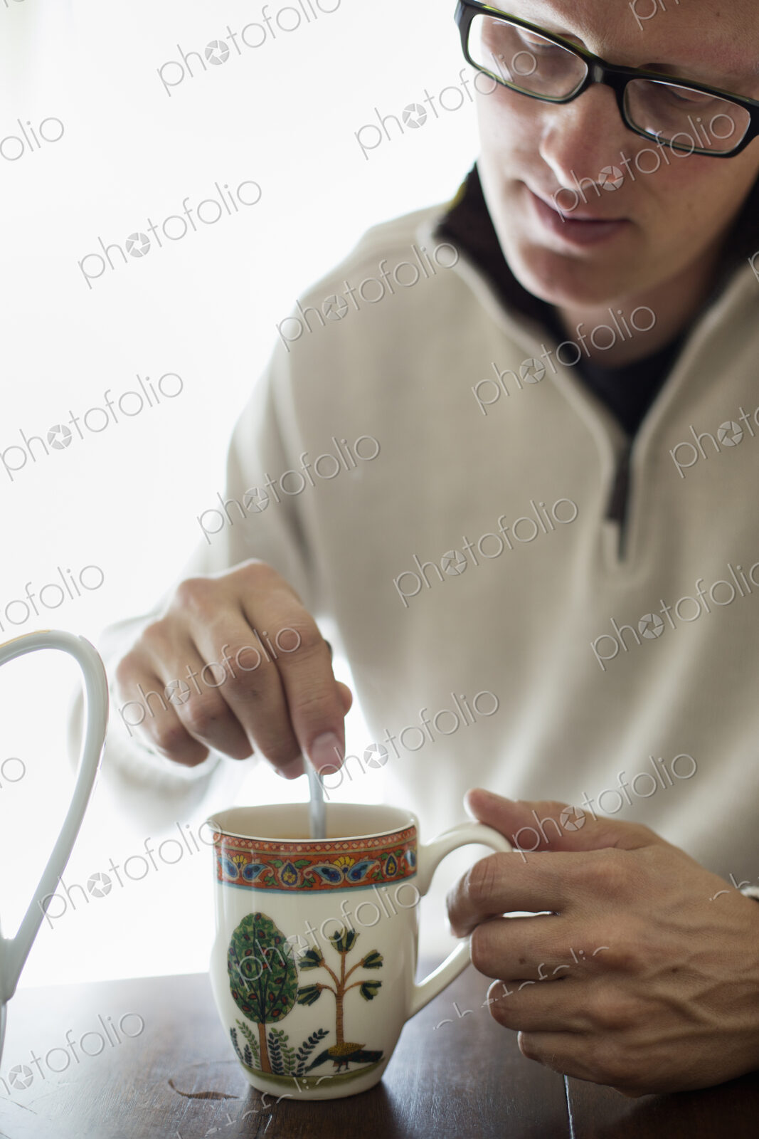 Man sitting at a table, stirring a cup of coffee.