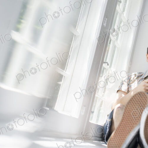 Man sitting by a window, holding a cell phone. Man sitting by a window, holding a cell phone.