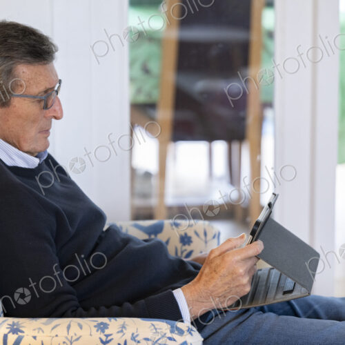 Man sitting in armchair using tablet.