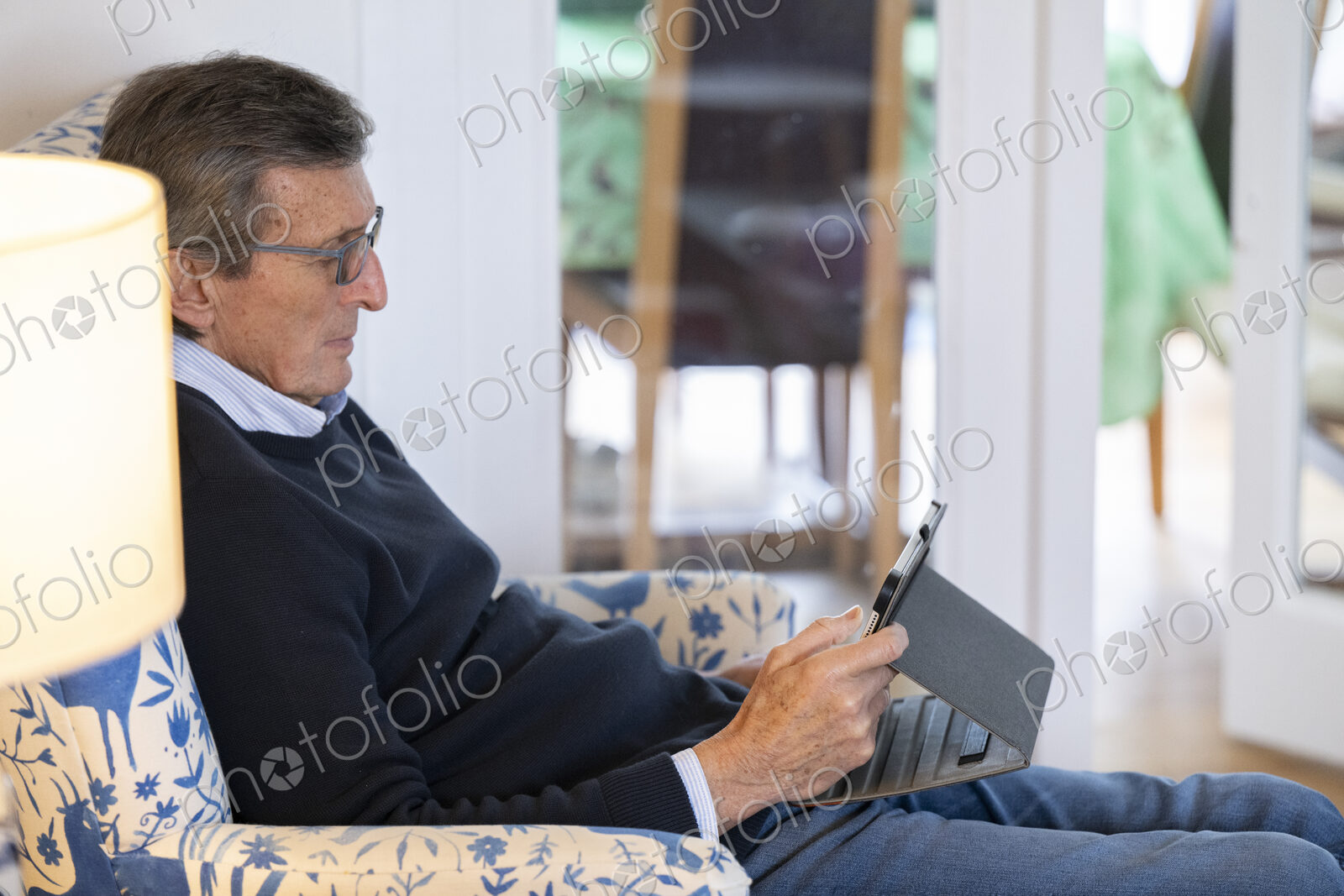 Man sitting in armchair using tablet.