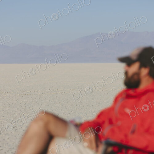 Man sitting in chair in vast, barren desert, blurred focus Man sitting in chair in vast, barren desert, blurred focus