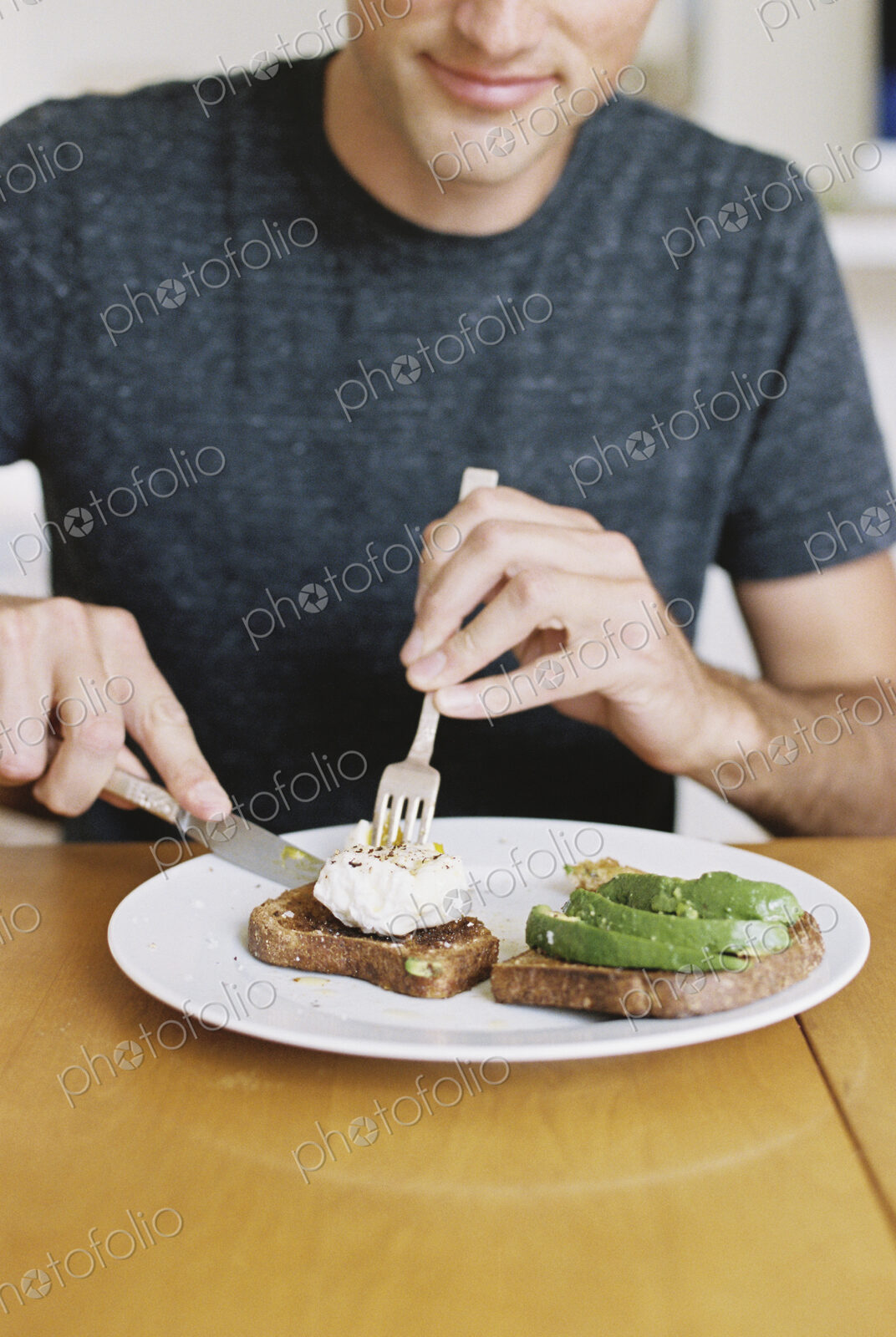 Man sitting in front of a plate of food at a table, eating.