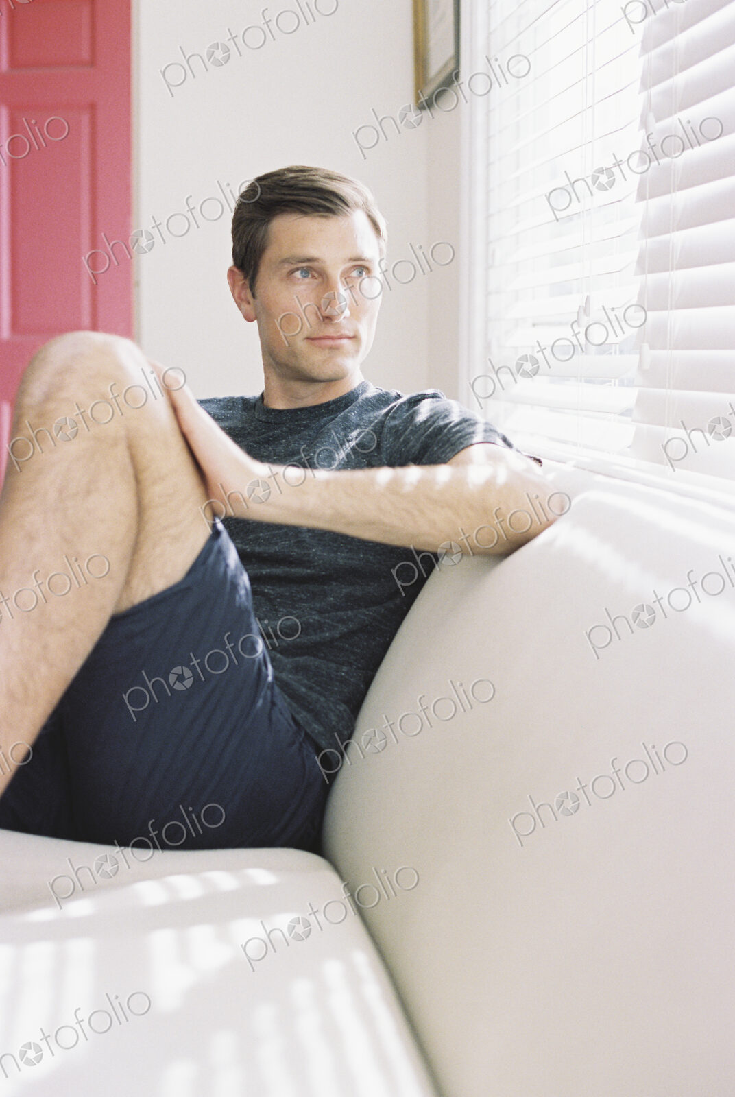 Man sitting on a sofa by a window, relaxing.