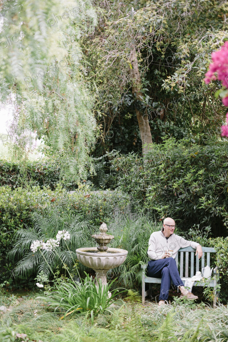 Man sitting on a wooden bench in a garden, taking a break.