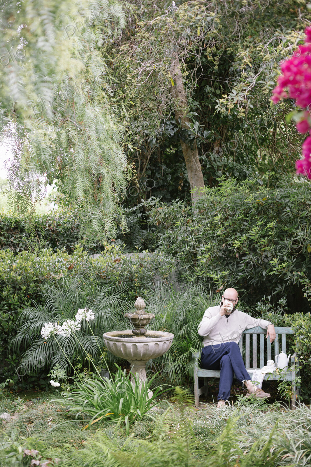 Man sitting on a wooden bench in a garden, taking a break.
