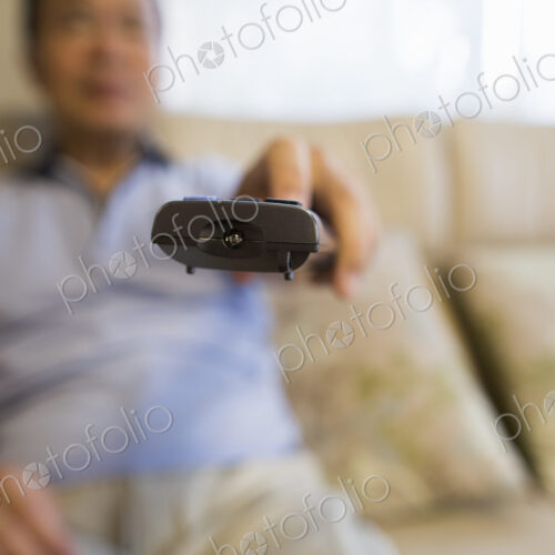 Man sitting on sofa holding remote control.