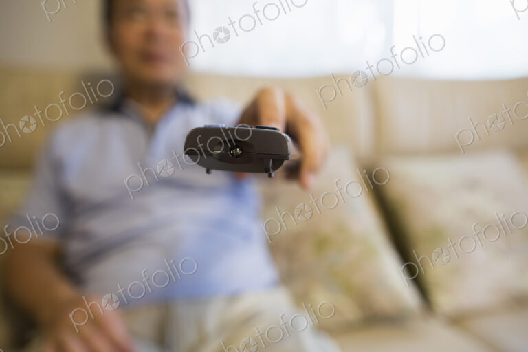 Man sitting on sofa holding remote control.