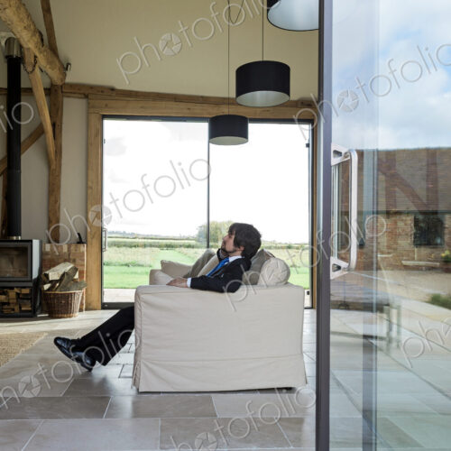 Man sitting on sofa in living room of converted barn house. Man sitting on sofa in living room of converted barn house.