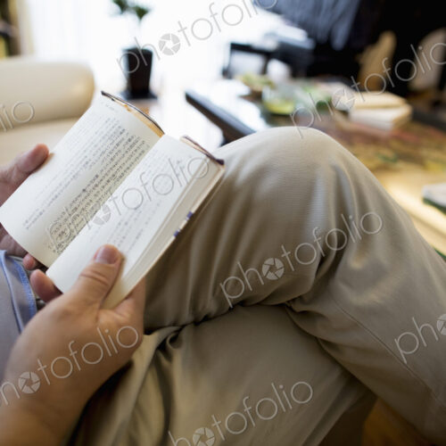 Man sitting on sofa reading a book.