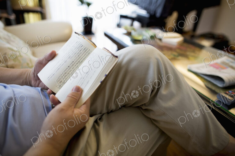 Man sitting on sofa reading a book.