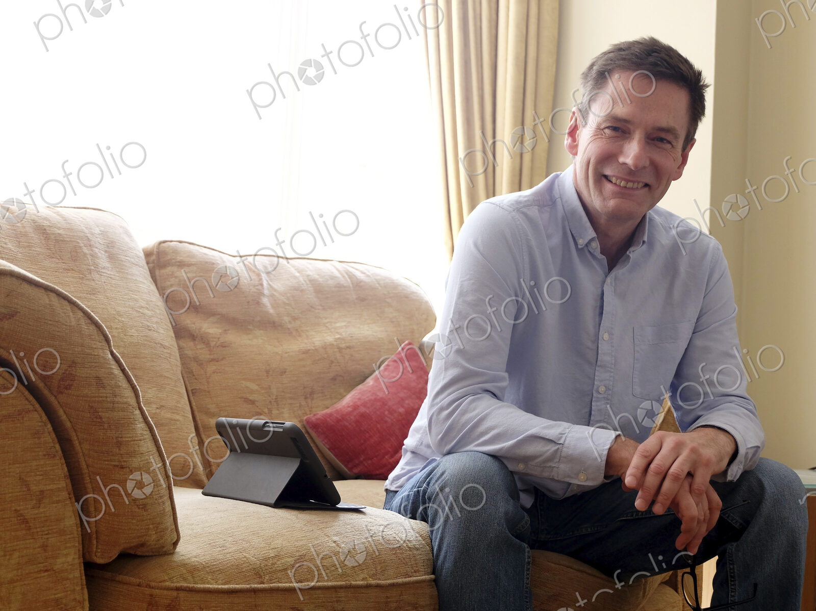 Man sitting on sofa smiling at camera.