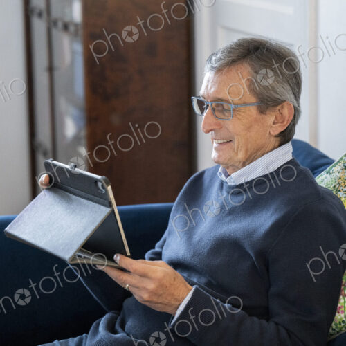 Man sitting on sofa using tablet.