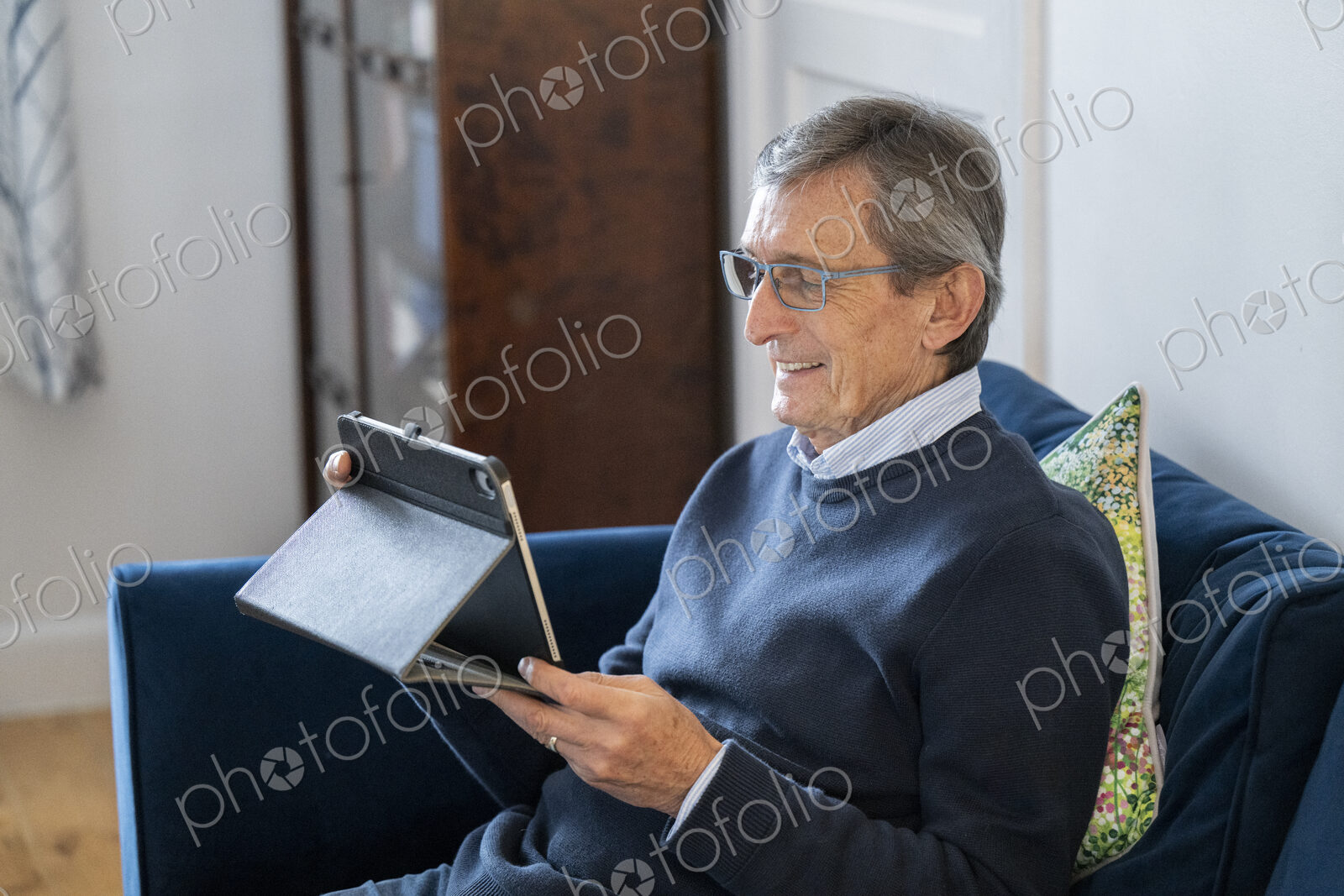 Man sitting on sofa using tablet.