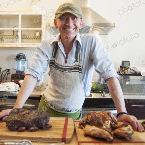 Man smiling with roasted meat in kitchen
