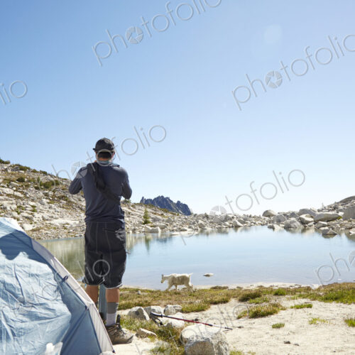 Man standing at tent at campsite near rural lake Man standing at tent at campsite near rural lake
