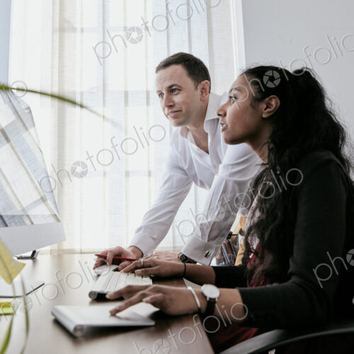 Man standing by a woman looking at a computer screen, Man standing by a woman looking at a computer screen,