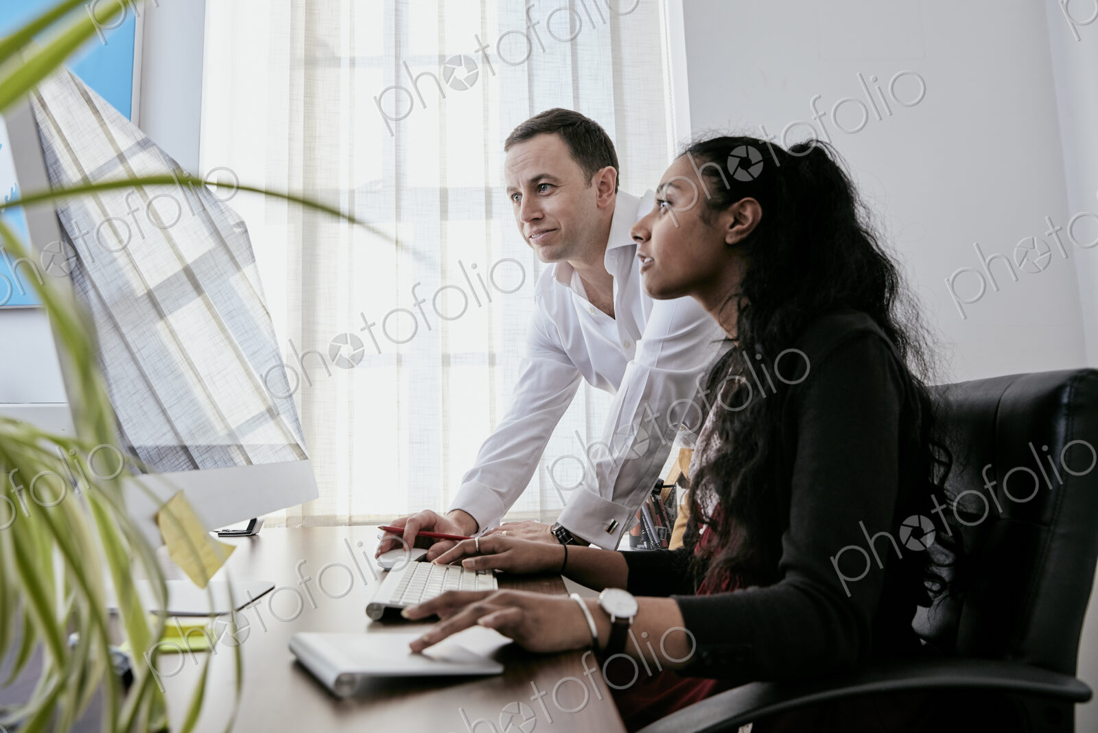 Man standing by a woman looking at a computer screen,