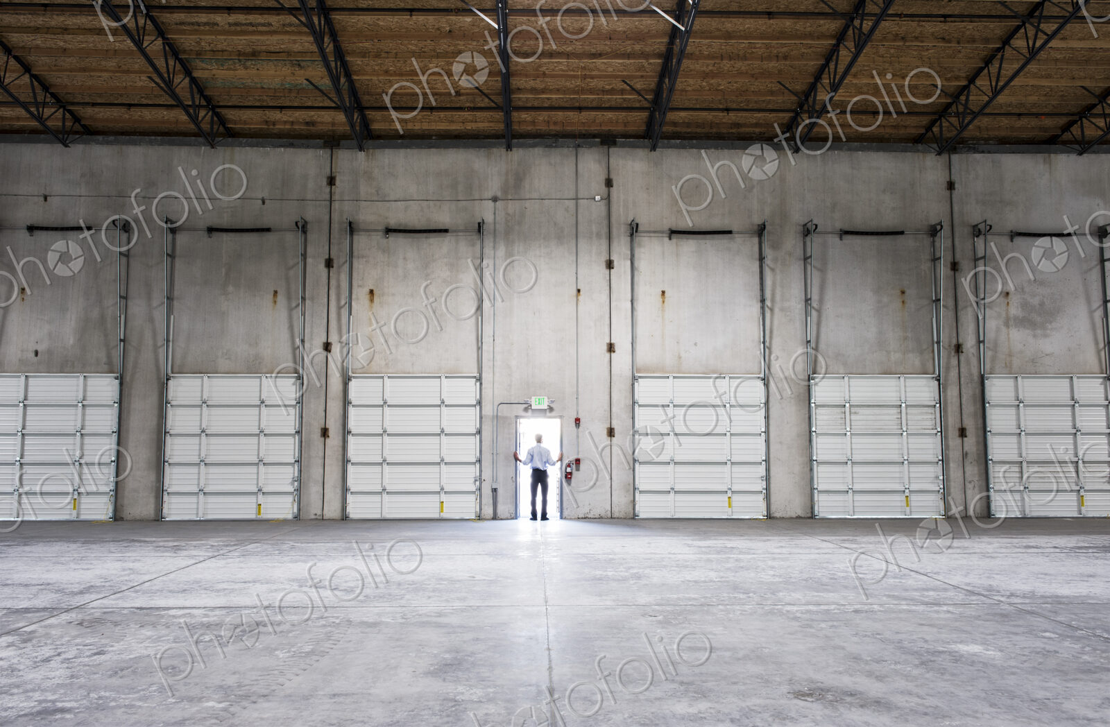 Man standing doorway of new warehouse waiting for the arrival of the first truck wiith…