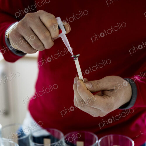 Man standing in a domestic kitchen, making jar candles. Man standing in a domestic kitchen, making jar candles.