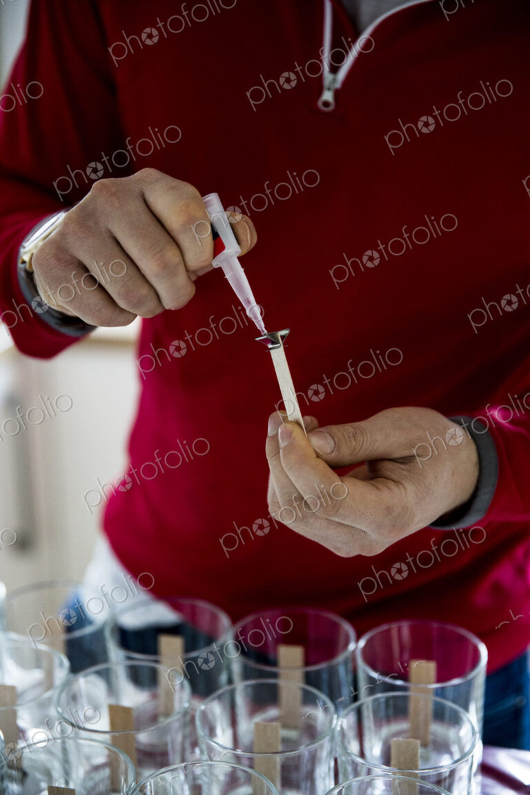 Man standing in a domestic kitchen, making jar candles.