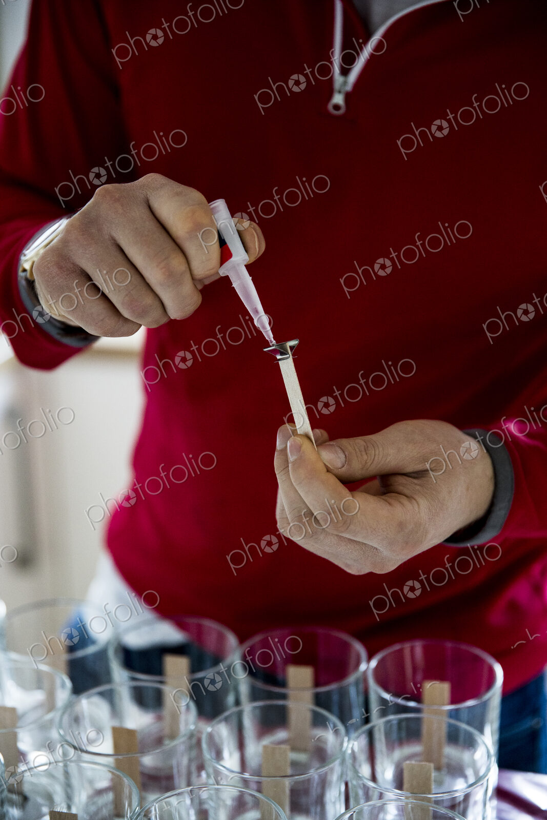Man standing in a domestic kitchen, making jar candles.