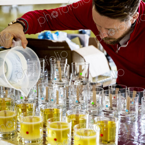 Man standing in a domestic kitchen, making jar candles.