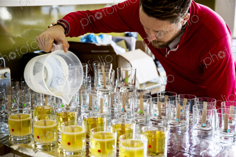 Man standing in a domestic kitchen, making jar candles.