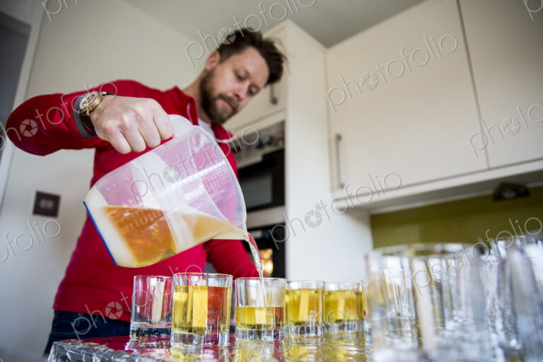 Man standing in a domestic kitchen, making jar candles.