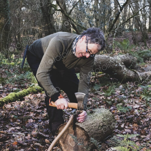 Man standing in forest, using axe and hatchet to split tree trunk. Man standing in forest, using axe and hatchet to split tree trunk.