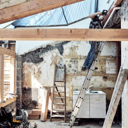 Man standing on a ladder working on a house extension Man standing on a ladder working on a house extension