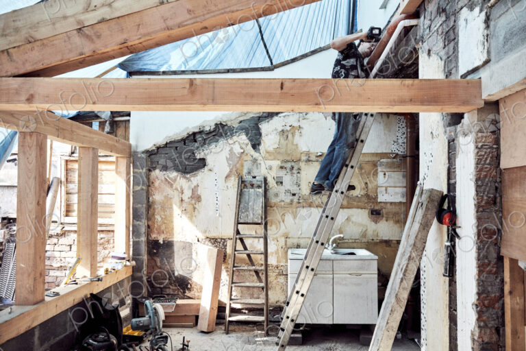Man standing on a ladder working on a house extension