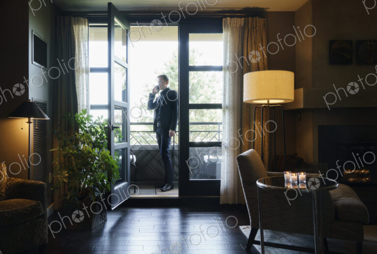 Man standing on hotel balcony talking on mobile telephone.