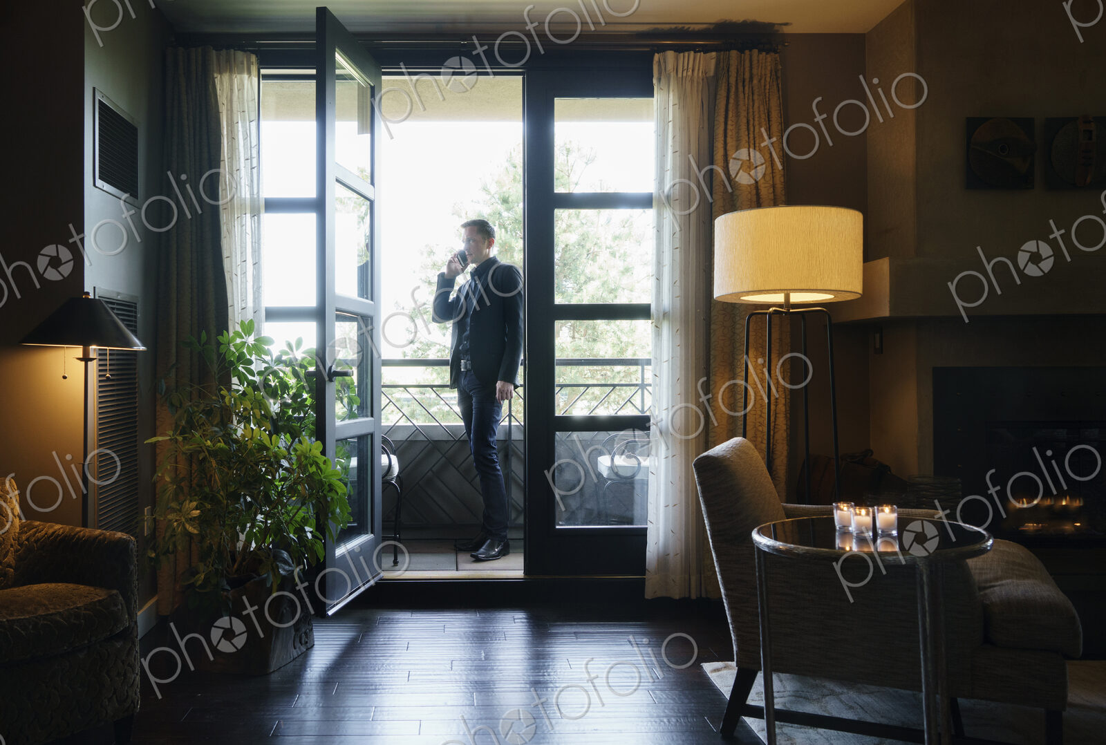 Man standing on hotel balcony talking on mobile telephone.