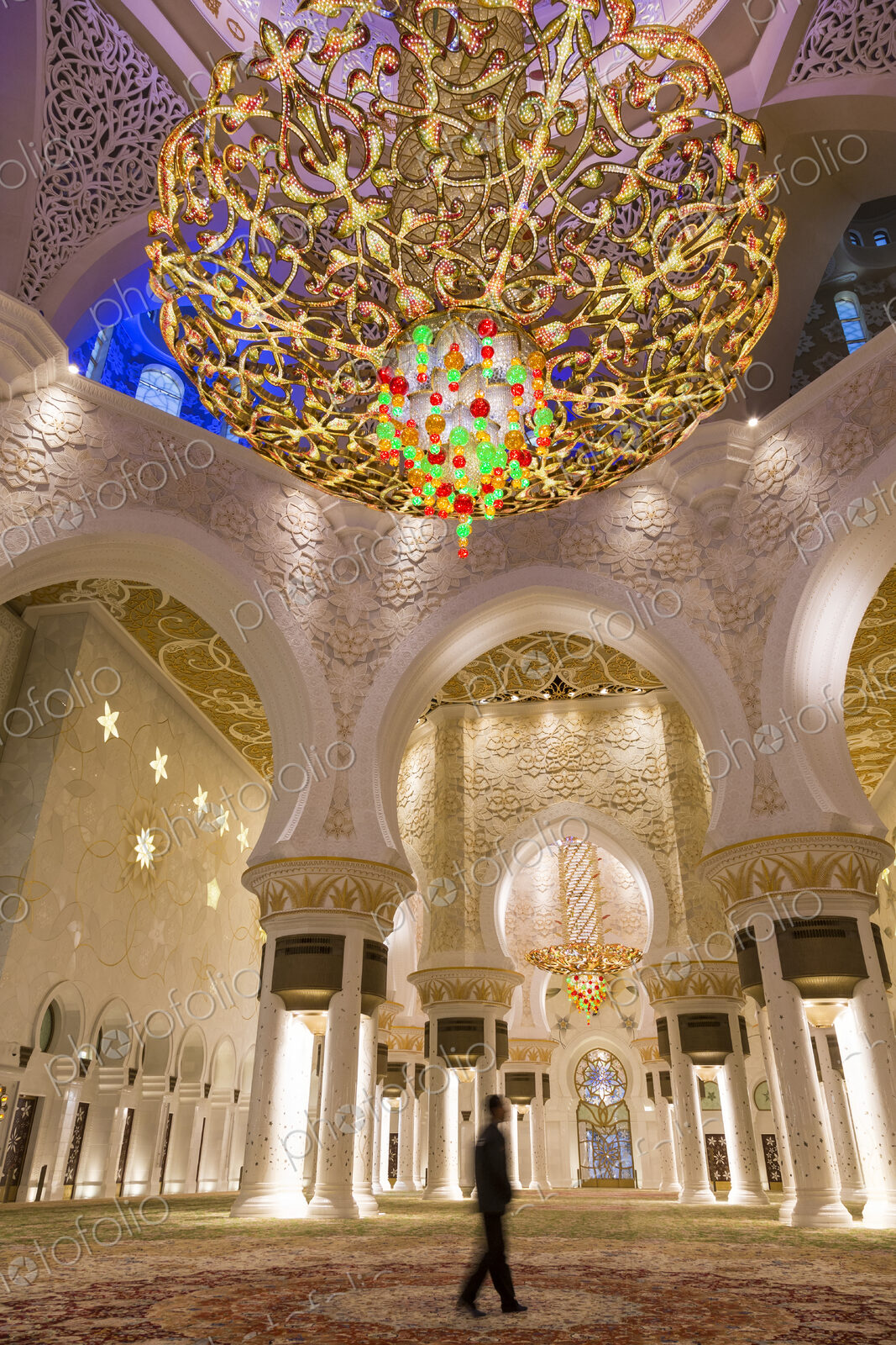 Man standing underneath white and golden dome of Sheikh Zayed Mosque