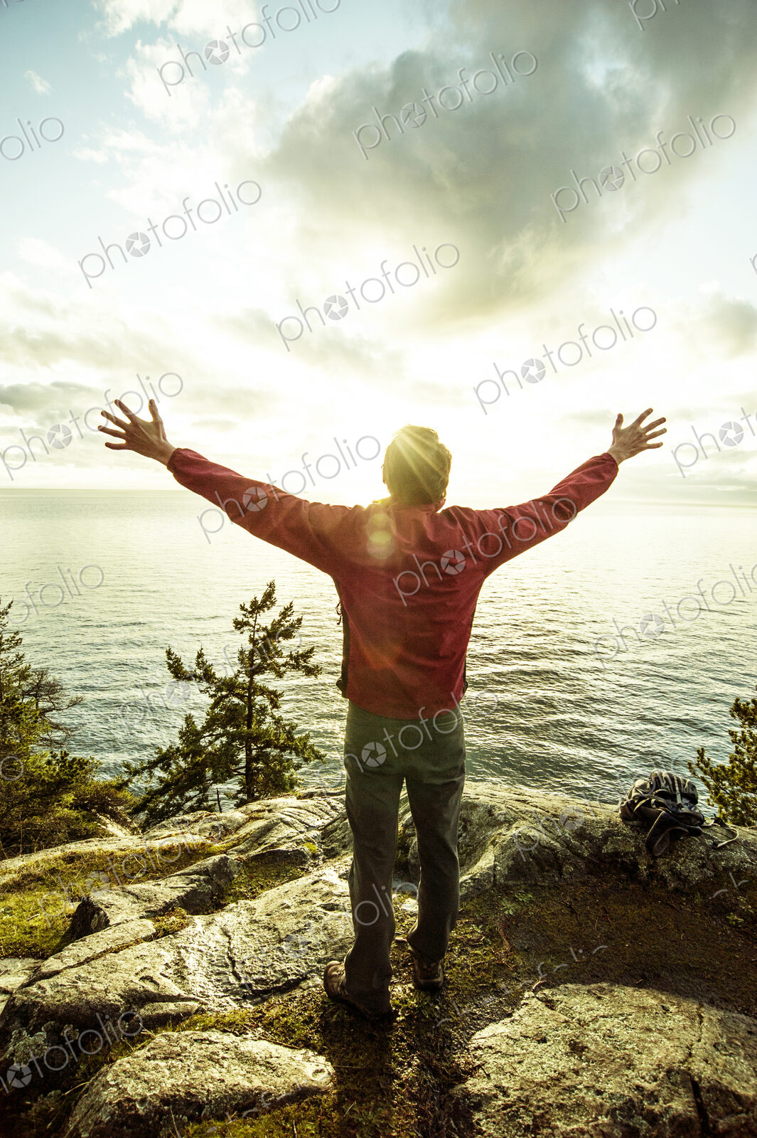Man standing with arms outstretched on rocks over ocean