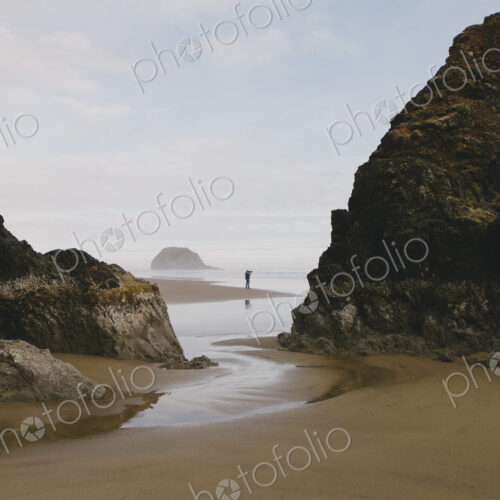 Man taking photographs on a beach at low tide, Arcadia Beach State Park, Oregon Man taking photographs on a beach at low tide, Arcadia Beach State Park, Oregon