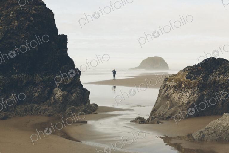 Man taking photos on beach at low tide, Arcadia Beach State Park, Oregon