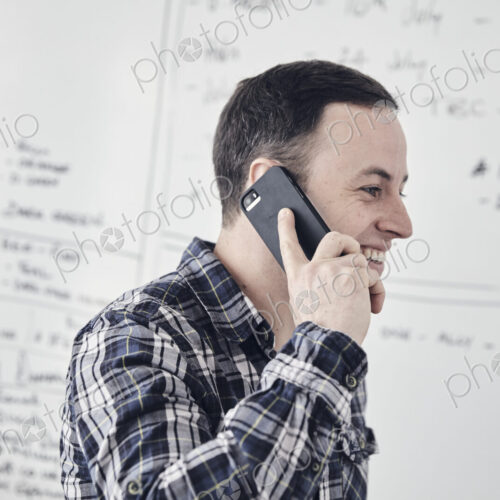Man talking on mobile phone in an office, by a whiteboard. Man talking on mobile phone in an office, by a whiteboard.