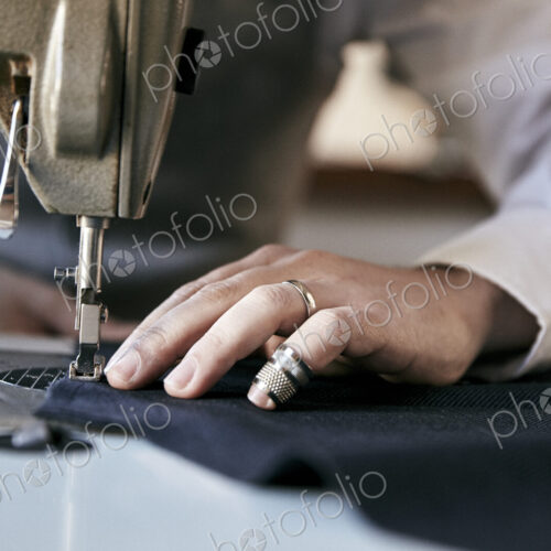 Man using an industrial sewing machine, stitching a garment. Man using an industrial sewing machine, stitching a garment.