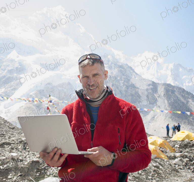 Man using laptop on snowy mountain