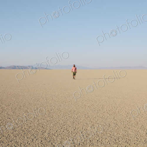 Man walking across a flat desert landscape
