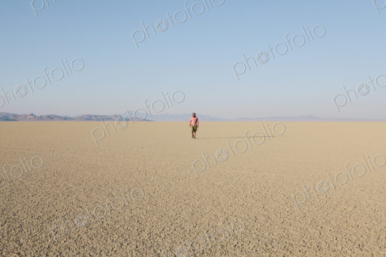 Man walking across a flat desert landscape