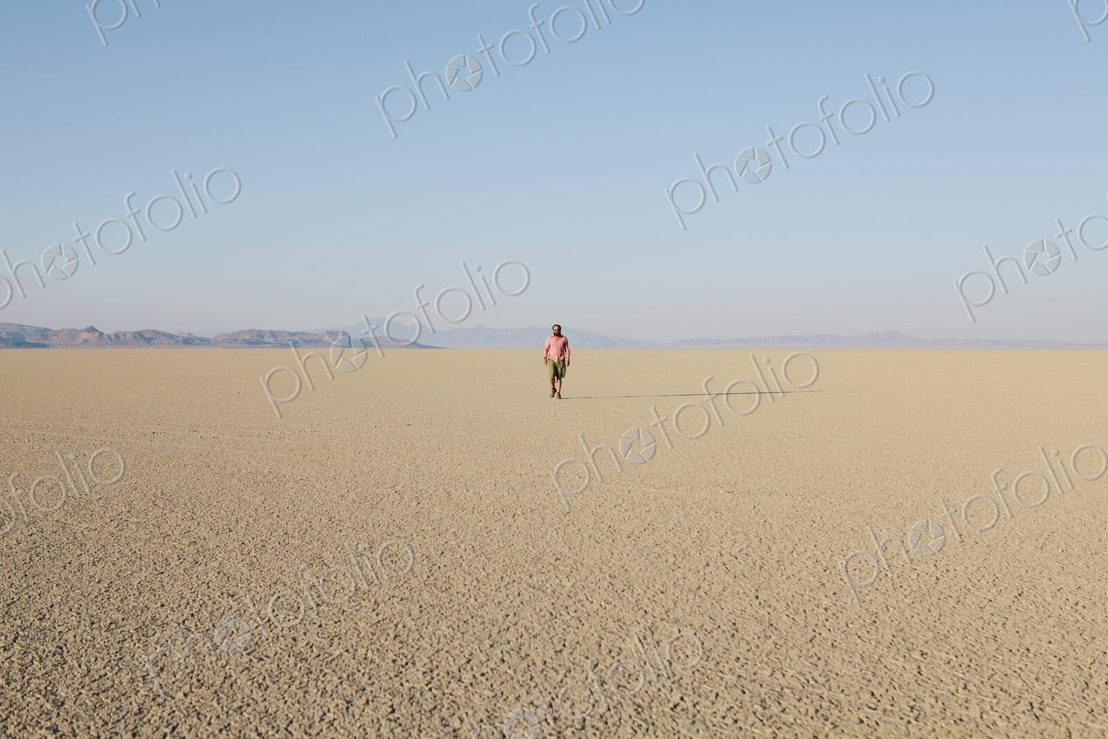 Man walking across a flat desert landscape