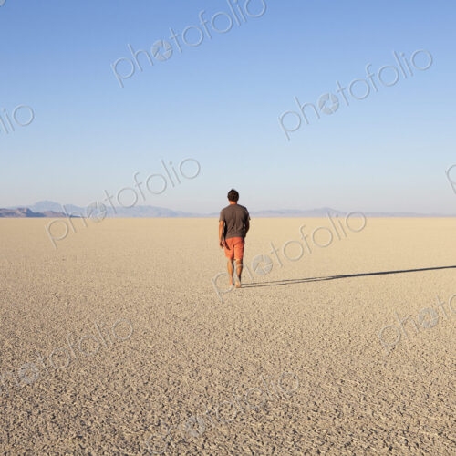 Man walking across a flat desert landscape