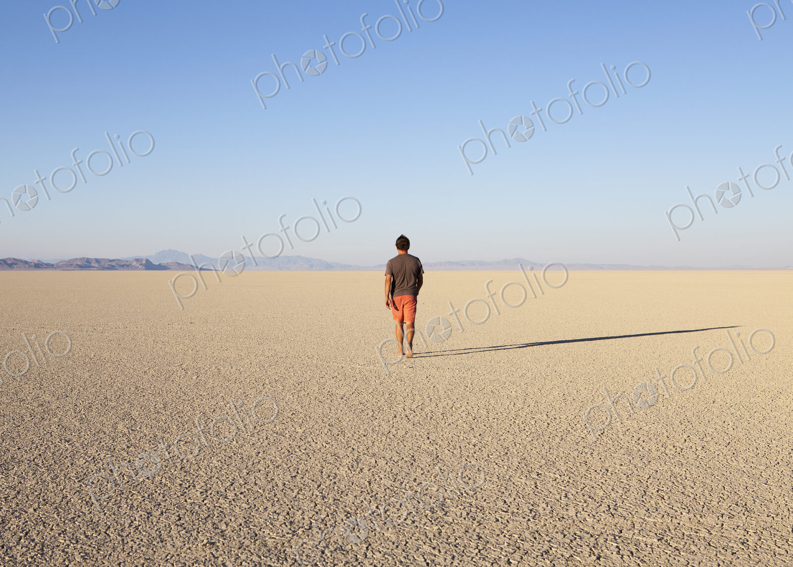 Man walking across a flat desert landscape