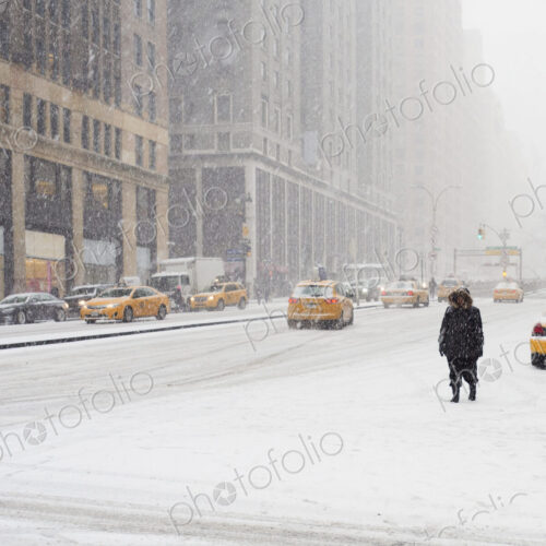 Man walking in a city in the snow during a blizzard, yellow taxis on the street. Man walking in a city in the snow during a blizzard, yellow taxis on the street.