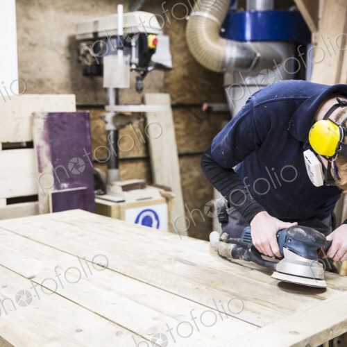 Man wearing ear protectors, protective goggles and dust mask standing in a warehouse,… Man wearing ear protectors, protective goggles and dust mask standing in a warehouse,…