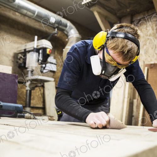 Man wearing ear protectors, protective goggles and dust mask standing in a warehouse,… Man wearing ear protectors, protective goggles and dust mask standing in a warehouse,…
