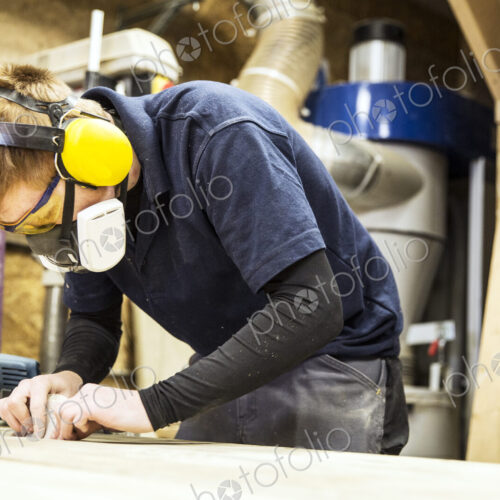 Man wearing ear protectors, protective goggles and dust mask standing in a warehouse,… Man wearing ear protectors, protective goggles and dust mask standing in a warehouse,…